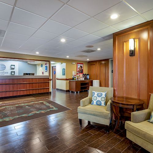 The image shows a hotel lobby with a reception desk, chairs, a table, and decorative pillows, all under bright lighting and a clean, modern design.